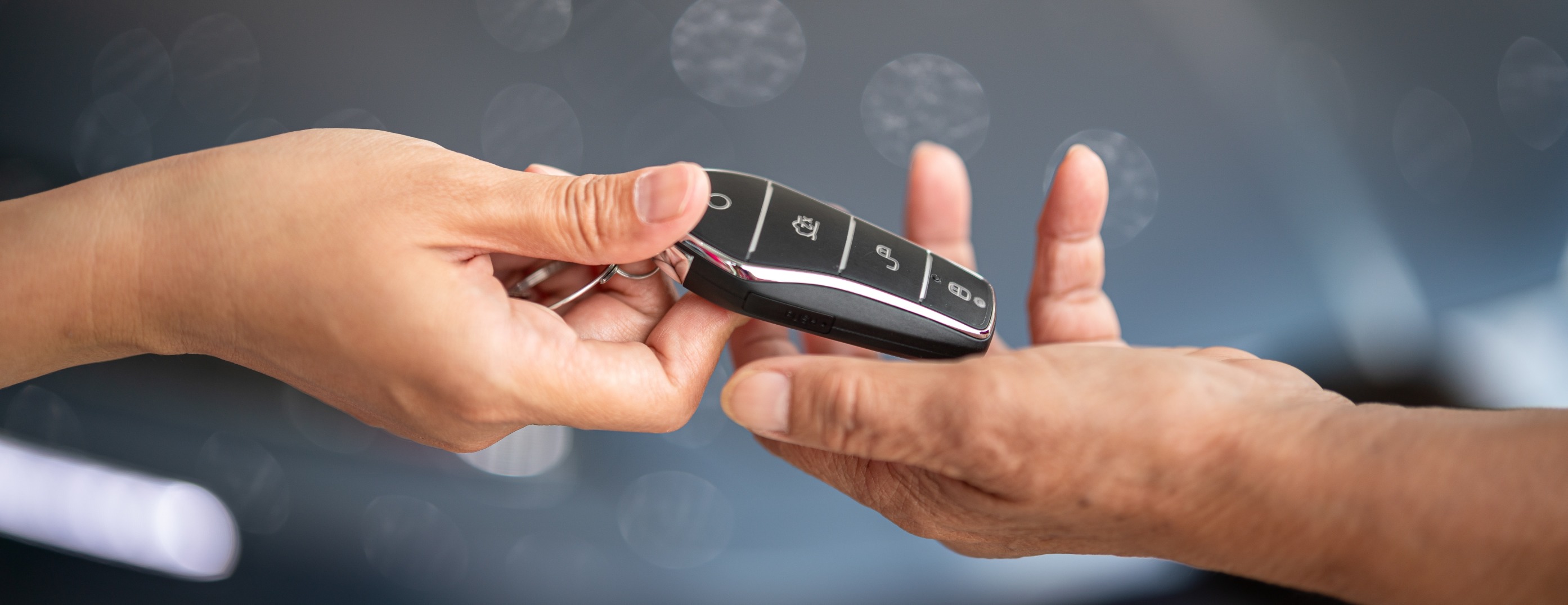 two hands exchanging a key for a new car